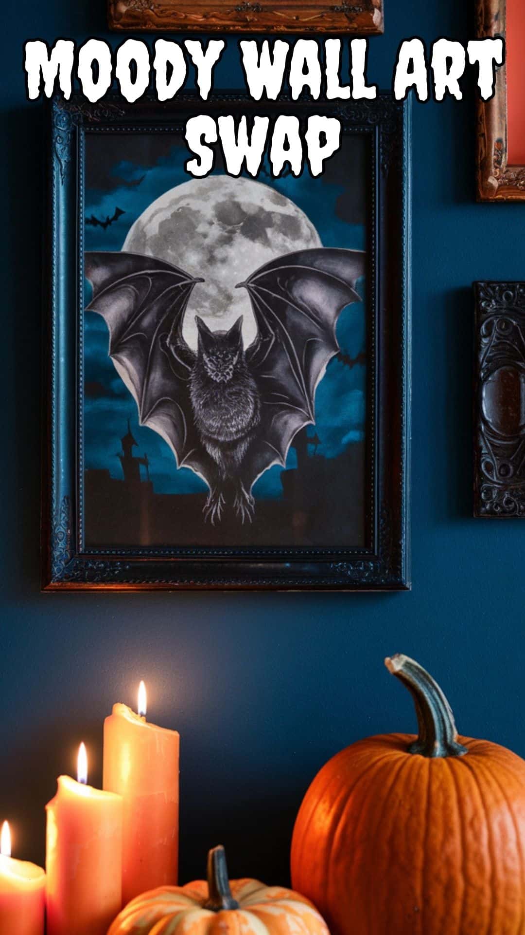A photo of a moody Halloween gallery wall with vintage bat and moon artwork in black frames. The wall is adorned with orange candles and pumpkins placed below the artwork.