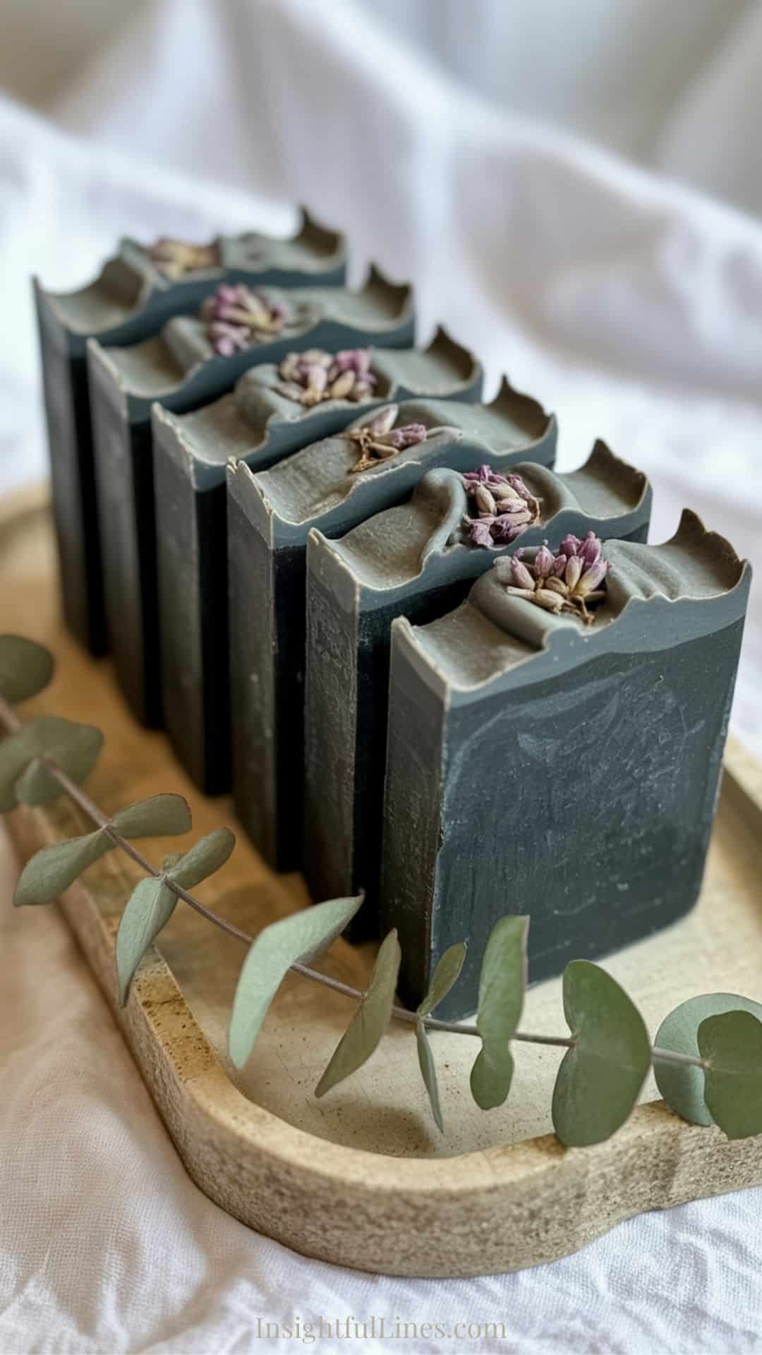 Activated charcoal soap bars with subtle dried botanical accents pressed gently into the top surface.